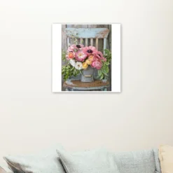 Roze, gele bloemen in vaas op stoel als sfeerimpressie aan de muur