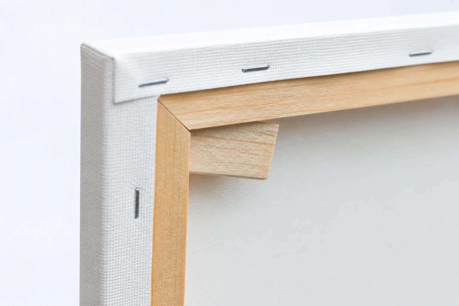 Het strak opspannen van katoenen doek op een houten schildersframe met wiggen