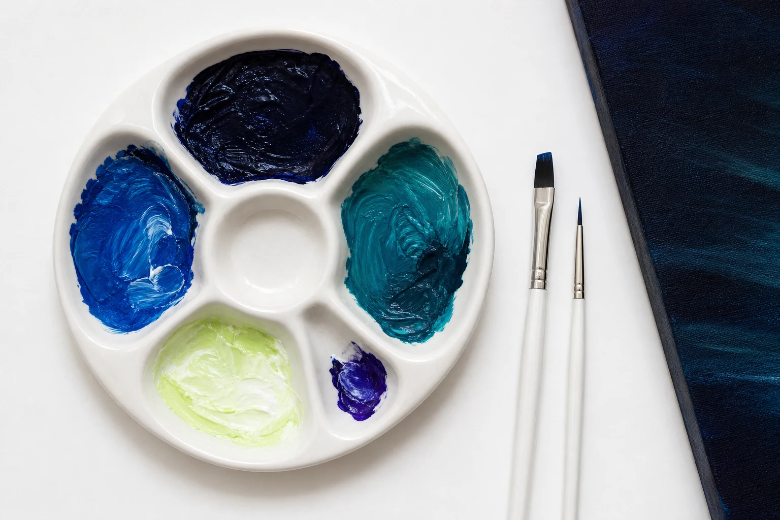 Wit schilderspalet met nachtblauw, helder blauw, blauwgroen, licht geelgroen en een klein violet accent