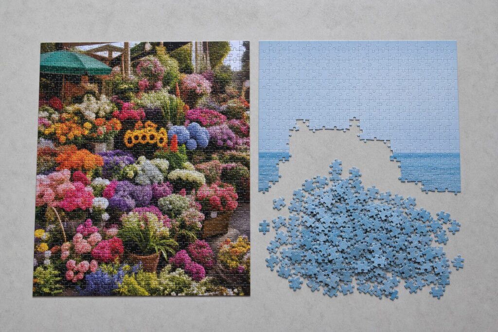 Twee puzzels naast elkaar: links een drukke bloemenmarkt bijna af, rechts een zeefoto met een berg identieke blauwe stukjes