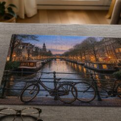 Afgemaakte fotopuzzel van een Amsterdamse gracht bij schemer, met een mok thee ernaast
