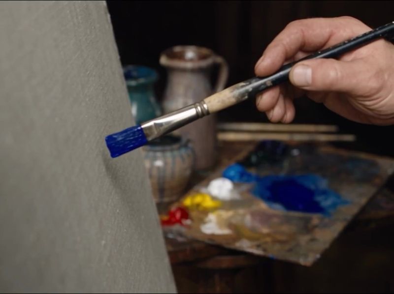 Still uit de AI-film: een plat penseel zet een blauwe streep op een leeg grijs doek