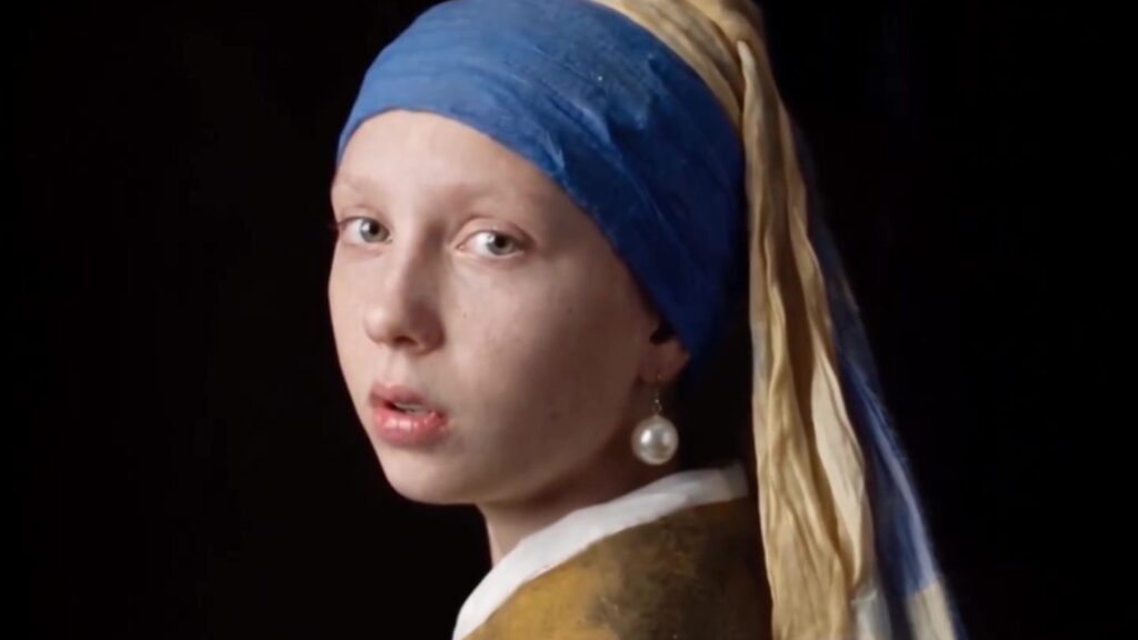 Meisje met de parel in de AI-film van el.cine: het meisje kijkt over haar schouder, met blauwe tulband en parel, tegen een zwarte achtergrond